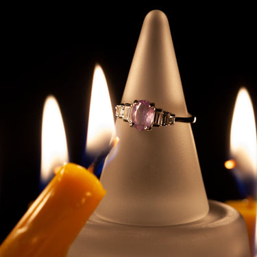 0.71ct natural alexandrite ring in 18k white gold with baguette diamond accents displayed on frosted cone with candle flames in background